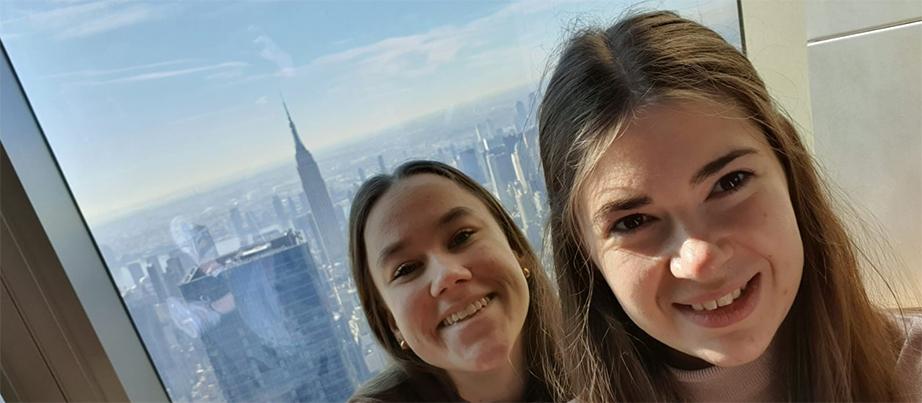 Foto: Eva und Luisa vor einem Fenster, im Hintergrund das Empire State Building