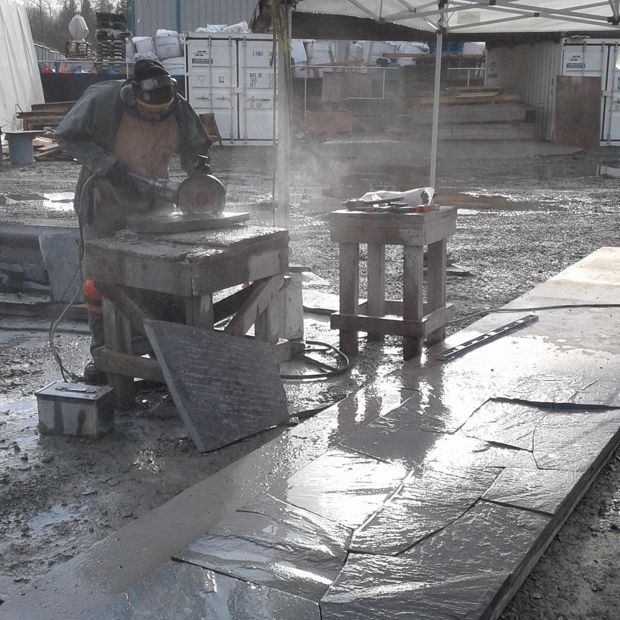 Eine Arbeiterin in Schutzkleidung die Stein schneidet unter einem Glasdach