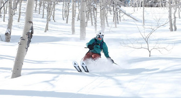 Foto: junger Mann fährt einen schneebedeckten Abhang auf Skiern hinab