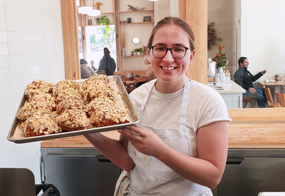 Auf dem Bild ist Charlotte bei der Arbeit mit einem Blech selbgemachter Croissants zu sehen.