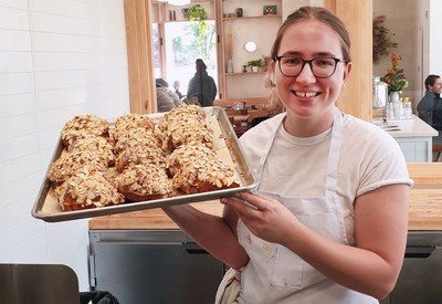Auf dem Bild ist Charlotte bei der Arbeit mit einem Blech selbgemachter Croissants zu sehen.