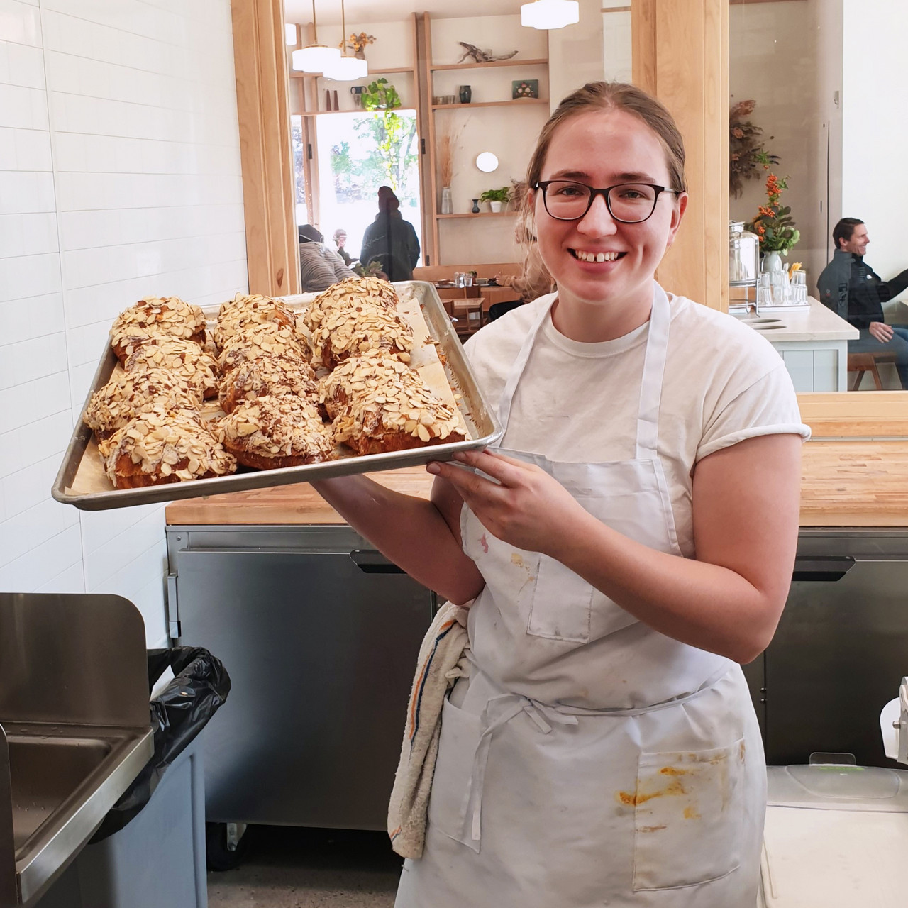 Auf dem Bild ist Charlotte bei der Arbeit mit einem Blech selbgemachter Croissants zu sehen.