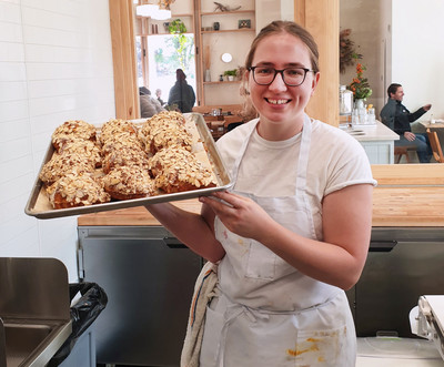 Auf dem Bild ist Charlotte bei der Arbeit mit einem Blech selbgemachter Croissants zu sehen.