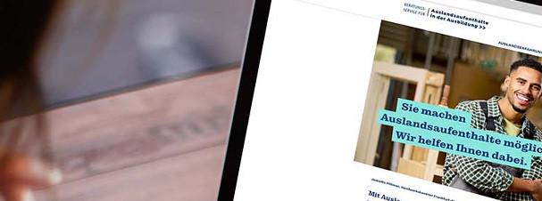 Foto: Person sitzt am Tisch vor Notebook und blickt auf Startseite des Portals