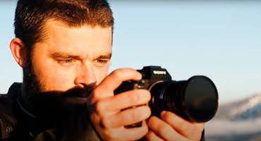 Foto: Henrik hält eine Kamera  und blickt auf das Display