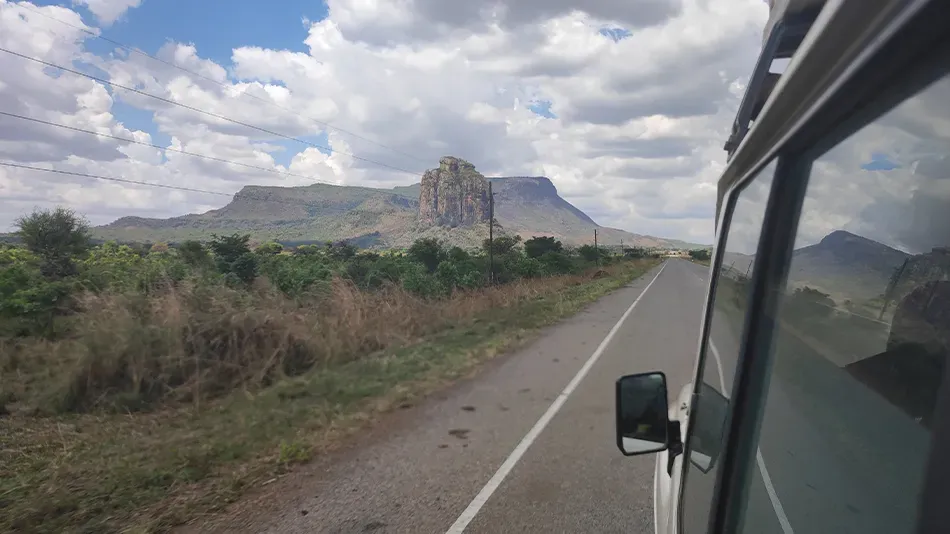 Aus einem Auto heraus sieht man in der Ferne einen Berg.