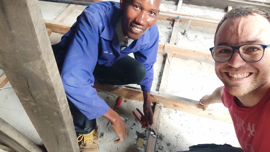 Selfie: Filbo und sein Arbeitskollege Matthew hocken auf dem Boden und l&auml;cheln in die Kamera.