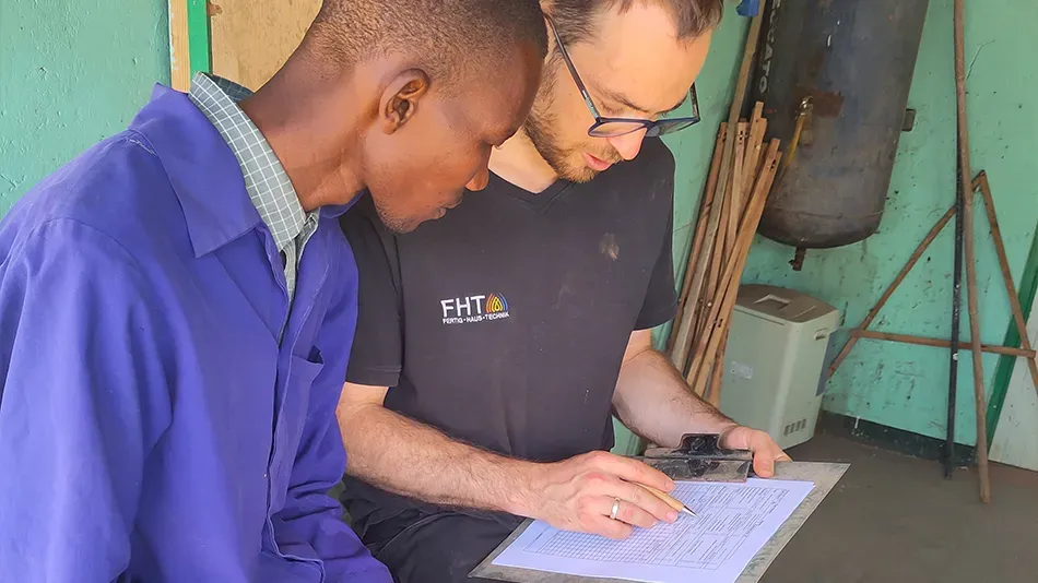 Filbo und sein Arbeitskollege Matthew blicken auf ein Klemmbrett.