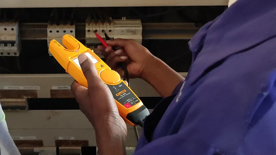 Eine Hand h&auml;lt einen Installationstester &ndash; ein Ger&auml;t, mit dem man Leitungen pr&uuml;fen kann. 