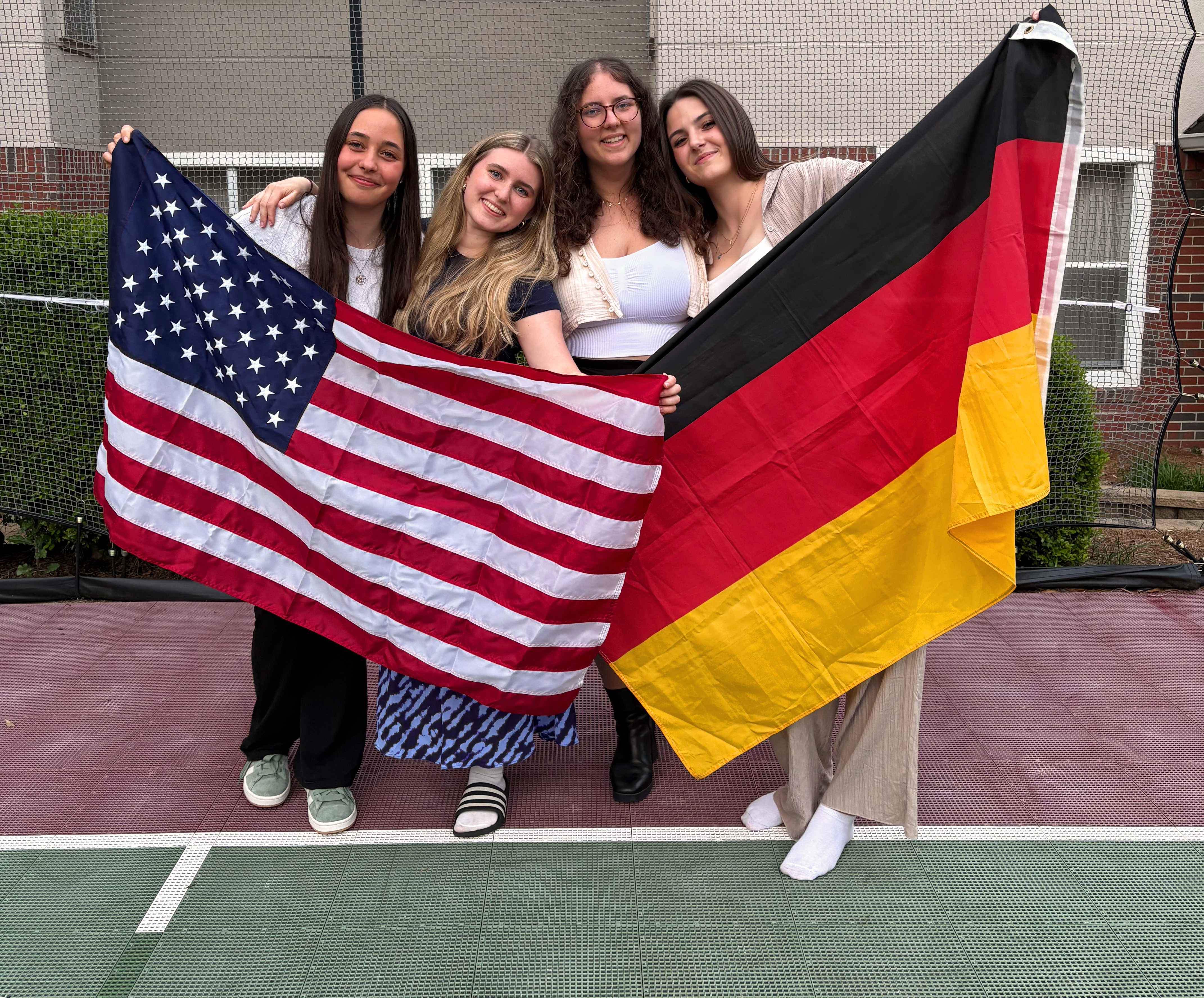 Auf dem Bild ist Jessica mit den anderen Auszubildenden zu sehen, wie sie eine Deutschland- und eine America-Fahne hochhalten.