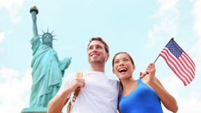 Mann und Frau mit Amerika Flagge und Freiheitsstatue im Hintergrund