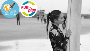 Foto:  Hanna steht am Strand neben ihrem Surfbrett und blickt aufs Meer
